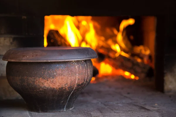 El fuego en el antiguo horno de pueblo tradicional ruso en un estilo rústico. Pote de sopa cerca de la leña ardiente — Foto de Stock