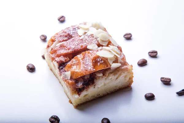 Pièce de tarte aux pommes isolée sur fond blanc avec flocons d'amandes et grains de café — Photo
