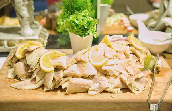 Slices of cold-smoked fish with lemon on  cutting board