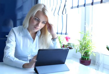 Güzel genç işkadını tablo yakınındaki onu Laptop oturuyor. 