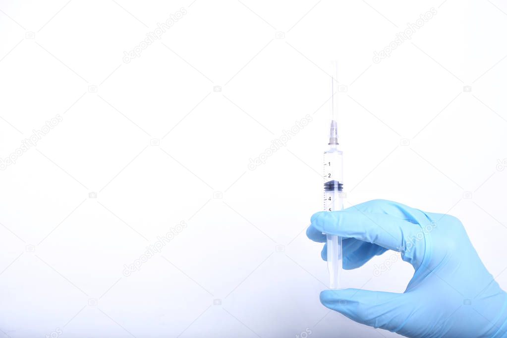 Man's hand in medical glove holds a syringe on white background. Medical concept. 