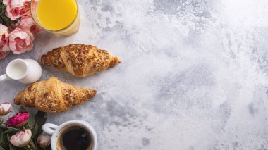 İçeceklerle nefis bir kahvaltı ve gri arka planda taze kruvasanlar. Üst Manzara. Boşluğu kopyala
