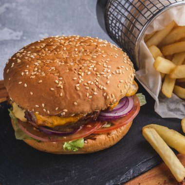 Tavuklu lezzetli burger, kırmızı soğanlı. Peynir, marul ve patates kızartması. Yakın çekim.