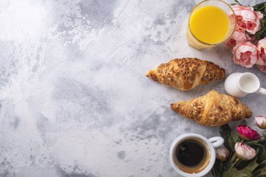 Kahve, meyve suyu ve gri arka planda taze kruvasanlarla nefis bir kahvaltı. Üst görünüm