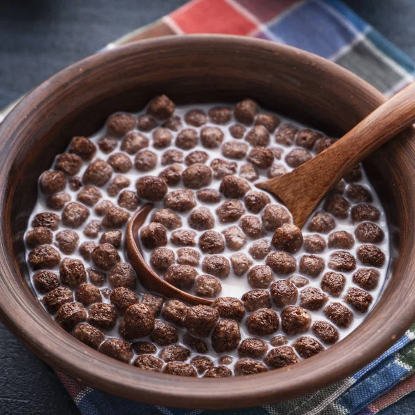 Boules de céréales au chocolat avec du lait dans un bol sur fond en bois. Gros plan — Photo