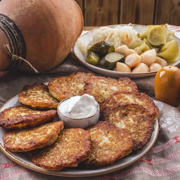 Leckere Kartoffelpuffer mit saurer Sahne auf einem Teller. — Stockfoto