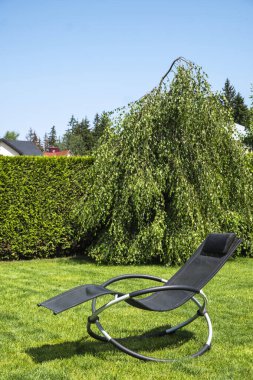 Yeşil çimlerin üzerinde sallanan bir şezlong. Dinlenme zamanı. Yakın çekim.