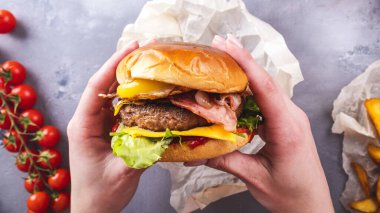 Lezzetli sığır burger tutan kadın elleri. Üst Manzara. Amerikan yemekleri.