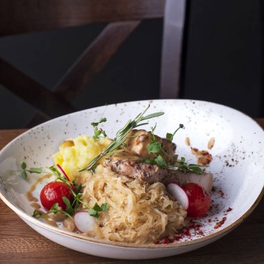 Kızarmış domuz eti, lahana turşusu ve patates püresinden garnitür.