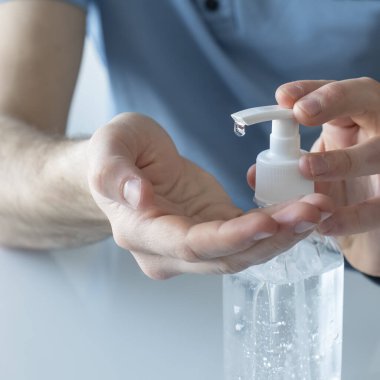 Elinde dezenfektan jel kullanan bir adamın yakın görüntüsü.