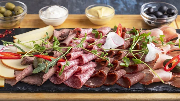 Closeup photo of sausages and smoked meats on wooden board.