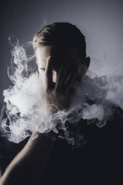 Önünde duman olan genç bir adam.