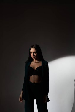 Sütyenli güzel esmer kadının stüdyo fotoğrafı mesafeye bakıyor.