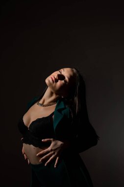 Sütyenli güzel esmer kadının stüdyo fotoğrafı mesafeye bakıyor.