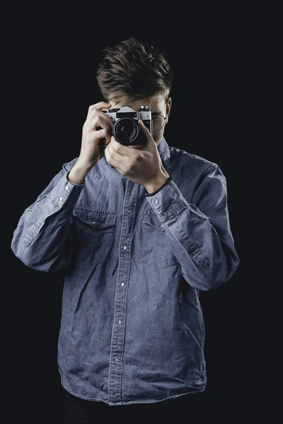 Мужчина, фотографирующий на старинную камеру. Человек на темном фоне с камерой . — стоковое фото