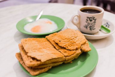 Geleneksel Singapur kahvaltı denilen Kaya tost, gevrek ekmek tost Hindistan cevizi reçeli, siyah kahve ve yarı haşlanmış yumurta