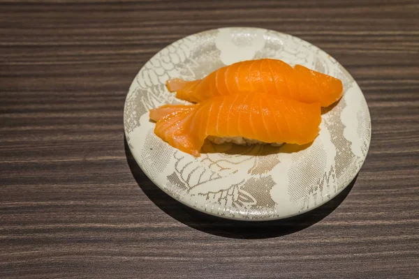 Sushi de salmão japonês fresco em prato branco na mesa de madeira — Fotografia de Stock