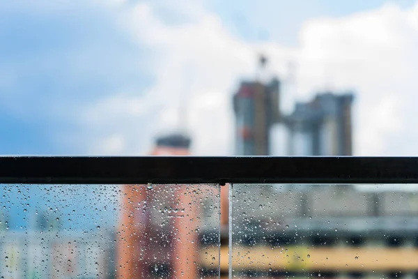 Rain drops on glass balcony and construction in background