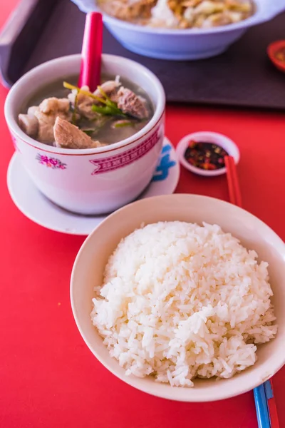 Sopa de costeletas de porco com arroz no fundo da mesa vermelha — Fotografia de Stock