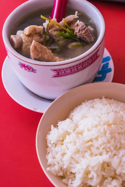 Sopa de costeletas de porco com arroz no fundo da mesa vermelha — Fotografia de Stock