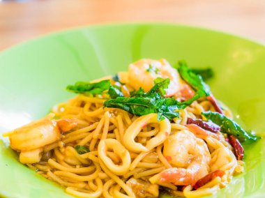 Acılı spagetti deniz ürünleri ahşap arka plan üzerinde yeşil bir tabak içinde