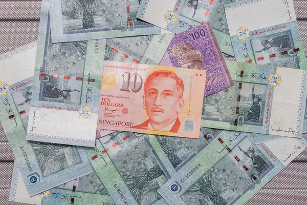 Singapore dollar on top of Malaysian Ringgit currency on backgro — Stock Photo, Image