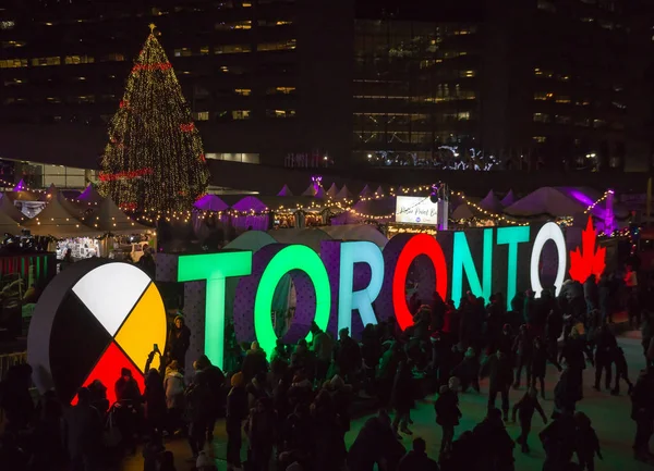 Toronto, Kanada 12. 23. 2018: Kanada 'nın en büyük şehri Toronto' daki Nathan Phillips Meydanı 'nda insanların Toronto tabelası ve Noel ağacı önünde buz pateni pistinde eğlendiği gece manzarası
