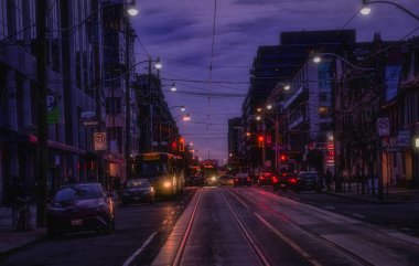 Eski Toronto bölgesindeki King caddesinde gece görüşü. Arabalar, trafik ışıkları ve sokak arabaları karanlıkta parlayan izler.