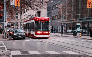 TORONTO, CANADA - 01 04 2020: Queen caddesinde, Sheraton Centre ve Four Seasons Centre 'ın önündeki trafik ışıklarında duran yeni bir Bombardier tramvay ve araba üretildi