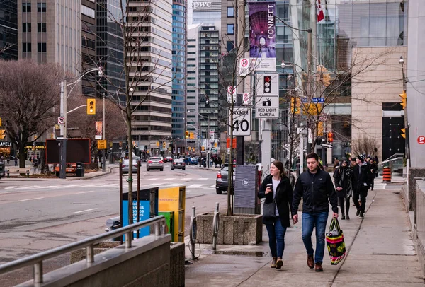 TORONTO, CANADA - 01 04 2020: Toronto, Ontario, Kanada şehir merkezinde arabaları ve yüksek binaları ile Üniversite Bulvarı 'ndaki kaldırımda yürüyen yayalar