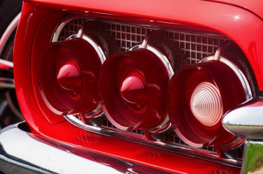 TORONTO, CANADA - 08 18 2018: Kırmızı ve beyaz cam külahlı arka kuyruk lambaları, kırmızı 1960 Ford Thunderbird 'ün parlak metal şebeke panelinde krom nozlarla çerçevelenmiş borular