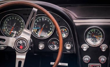 TORONTO, CANADA - 08 18 2018: 1966 Chevrolet Corvette Sting Ray Oldtimer arabasının ön panelinde logosu ve tuşları olan direksiyon simidi Danforth otomobil fuarında sergileniyor