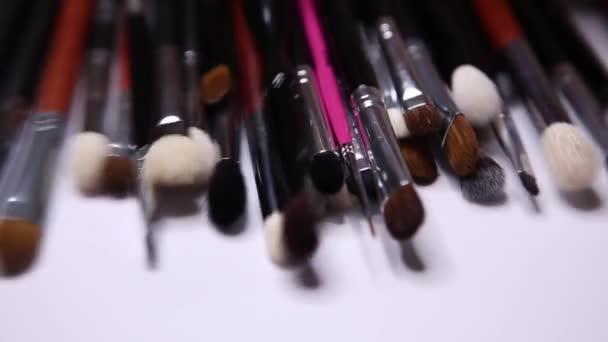 Set van make-up borstels, borstels voor cosmetica van verschillende maten. overzicht van de gereedschappen van een make-up kunstenaar. Leg borstels van zijn handen op de tafel.. — Stockvideo