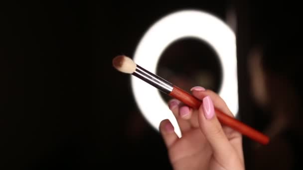 A girl drives a brown makeup brush through the air on a black background — Stock Video