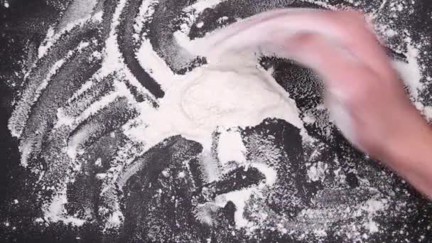 Hand collects and sprinkles flour on a black table. View from above — ストック動画