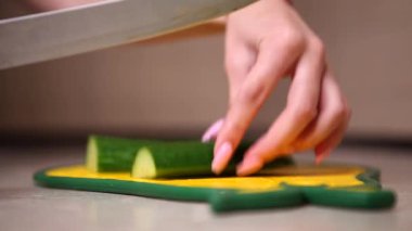 Kız sarı bir postta salatalık kesiyor.