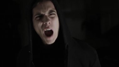 Man suffering from stress, mental illness, rage, failure, parting with a girl. Screaming on a black background with dramatic light