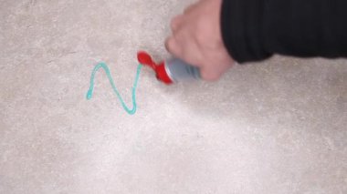 Bej bir mutfak masasına mavi deterjan döküp sarı bir bez parçasıyla temizlik yapmak.