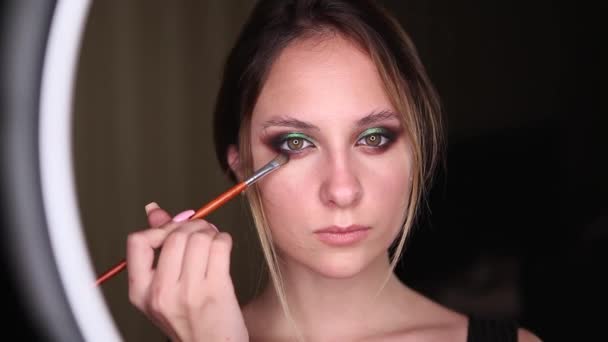 Primo piano di ragazza make-up artist pittura occhi e l'applicazione di mascara. Fa trucco degli occhi su uno sfondo nero . — Video Stock