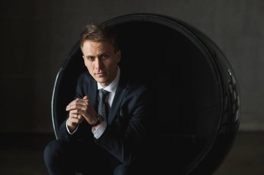 gri arka plan üzerinde sandalyede oturan genç işadamı