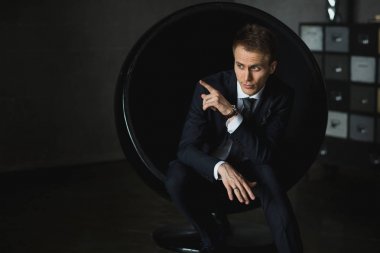 gri arka plan üzerinde sandalyede oturan genç işadamı