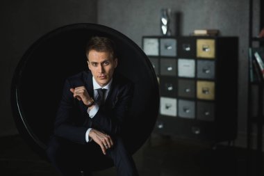 gri arka plan üzerinde sandalyede oturan genç işadamı