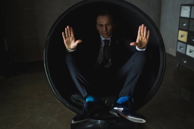 genç işadamı gri arka plan üzerinde sandalyede oturarak poz duygusal