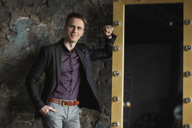 Mutlu gülümseyen yakışıklı adam ayakta ve kameraya gri arka plan üzerinde seyir siyah elbiseli