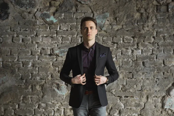 Mutlu gülümseyen yakışıklı adam ayakta ve kameraya gri arka plan üzerinde seyir siyah elbiseli