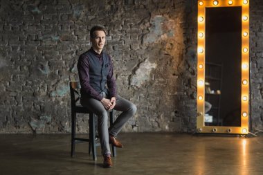 Siyah elbiseli kameraya bakarak mutlu gülümseyen yakışıklı adam