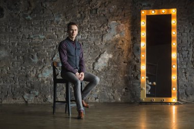 Siyah elbiseli kameraya bakarak mutlu gülümseyen yakışıklı adam