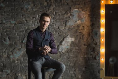 Mutlu gülümseyen yakışıklı adam kameraya gri arka plan üzerinde seyir siyah elbiseli