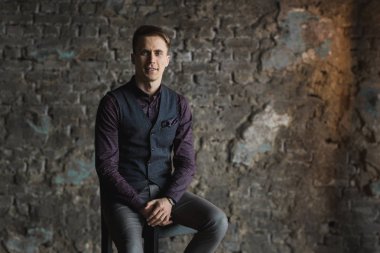 Mutlu gülümseyen yakışıklı adam kameraya gri arka plan üzerinde seyir siyah elbiseli