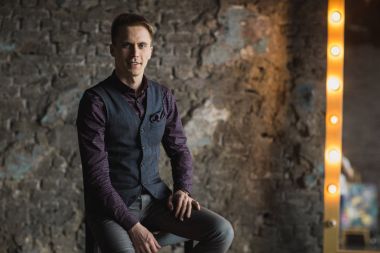 Mutlu gülümseyen yakışıklı adam kameraya gri arka plan üzerinde seyir siyah elbiseli